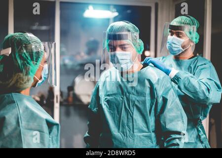 Medici e infermieri si preparano a lavorare in ospedale per l'intervento chirurgico durante l'epidemia di coronavirus pandemic - operatori medici che si vestono all'interno c Foto Stock