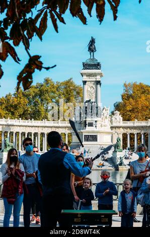 Man esegue un pericoloso trucco di giocoleria con la spada ad un pubblico al Retiro Park di Madrid, Spagna Foto Stock