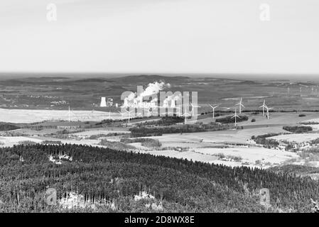 Vista delle turbine eoliche nei pressi di Hradek nad Nisou, Repubblica Ceca, in contrasto con la centrale a carbone Turow, Bogatynia, Polonia. Luogo di conflitto internazionale sull'espansione della centrale elettrica. Immagine in bianco e nero. Foto Stock