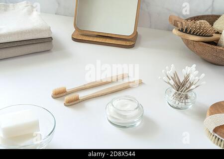 Concetto di zero sprechi. Set di accessori da bagno ecologici - spazzolini da denti in bambù, boccioli di cotone, spazzola per capelli naturali, specchio e nappine di lino. Stile di vita sostenibile. Foto Stock