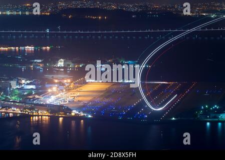 Rio de Janeiro Santos Dumont di notte in Brasile. Lunga esposizione che mostra le tracce di luce dell'aereo durante il decollo. Aereo in partenza da pista leggera. Foto Stock