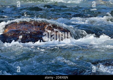 Un'immagine ravvicinata di una grande roccia nella Fiume Maligne con l'acqua che scorre intorno ad esso Foto Stock