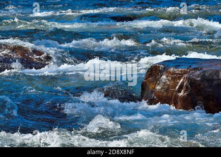 Un'immagine ravvicinata di una grande roccia nella Fiume Maligne con l'acqua che scorre intorno ad esso Foto Stock