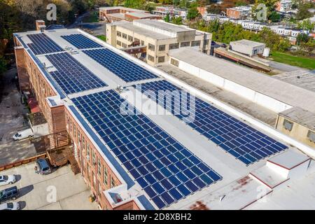 sei grandi gruppi di pannelli solari per generare energia rinnovabile in cima ad un ex edificio di fabbrica che è stato trasformato in appartamenti moderni Foto Stock