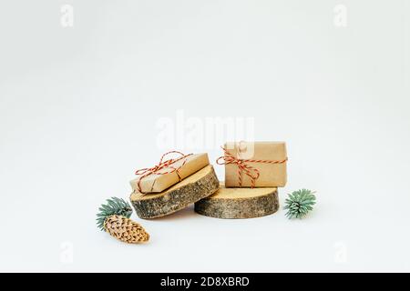 Due regali artigianali sui cilindri rotondi di legno forme sullo sfondo chiaro. Concept Natale e Capodanno. Spazio di copia. Foto Stock