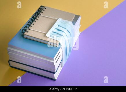 Libri impilati legati con maschera facciale. Ritorno a scuola durante il concetto di coronavirus. Foto Stock
