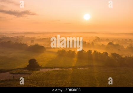 Paesaggio naturale con il sole che sorge sopra il paese coperto di nebbia. Foto Stock