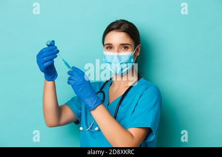 Concetto di covid-19 e concetto di quarantena. Immagine del medico femminile in maschera medica, guanti e scrub, siringa di riempimento con il vaccino del coronavirus