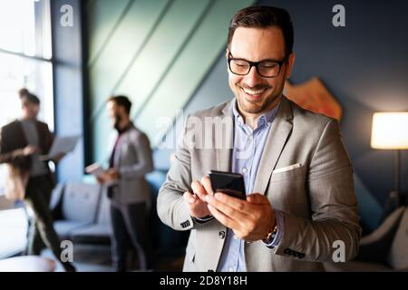 Bell'uomo d'affari che controlla le e-mail al telefono in ufficio moderno Foto Stock