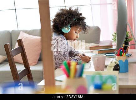 Scuola africana ragazzina indossando le cuffie Virtual distance learning a casa. Foto Stock