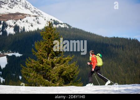 Montagne innevate, alberi verdi e scialpinista facendo sci alpinismo in giornata di sole. Neve e attività invernali, sciare in montagna. Foto Stock