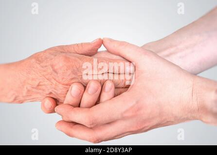 L'uomo tiene le mani di donna anziana. Concetto di assistenza e assistenza senior. Foto Stock