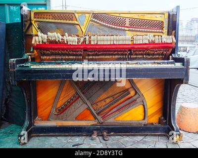 Un vecchio pianoforte rotto è sulla strada. Vista frontale Foto Stock