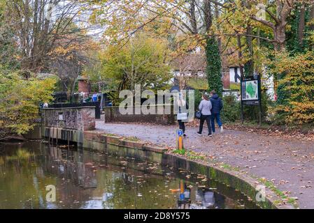 Le persone fuori e in giro nel Parco Verulamium camminano verso il ponte sul fiume Ver all'ingresso del parco. St. Albans, Hertfordshire, Inghilterra, Regno Unito Foto Stock