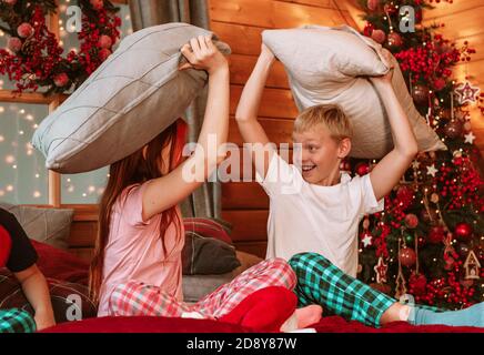 tre bambini in pigiama sul letto che hanno combattimenti cuscino La mattina di Natale Foto Stock