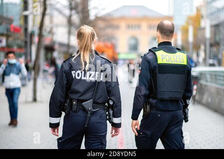 02 novembre 2020, bassa Sassonia, Hannover: Gli agenti di polizia controllano nella zona pedonale il rispetto dell'obbligo di mascheramento. Sullo sfondo è possibile vedere la stazione principale. A seguito di un aumento delle infezioni da corona nella regione di Hannover, le maschere sono obbligatorie per le aree molto frequentate negli spazi pubblici. Foto: Hauke-Christian Dittrich/dpa Foto Stock