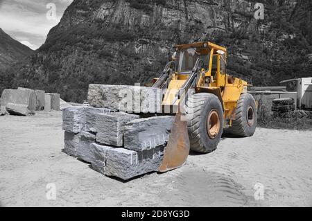 Macchina Digger gialla con blocchi di pietra nella Valle della Svizzera. Foto Stock