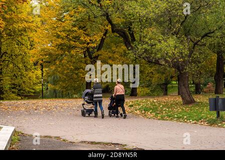 Due madri camminano e parlano mentre prendono i loro capretti Per una passeggiata nel parco Letna Nell'autunno 2020 a Praga 6 durante la quarantena pe Foto Stock