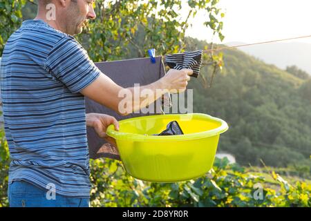 Uomo che appende fuori i vestiti ad asciugare. Concetto di lavoro domestico. Foto Stock