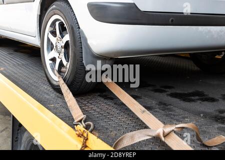 Vettura allacciata con cinghia di sicurezza sul carrello di traino con pianale Foto Stock