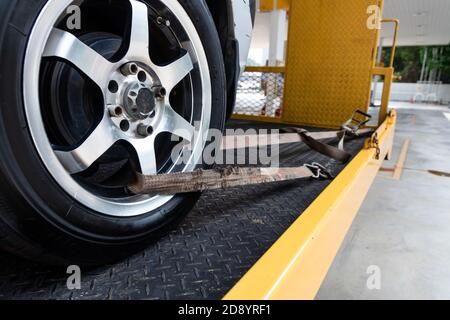 Vettura allacciata con cinghia di sicurezza sul carrello di traino con pianale Foto Stock