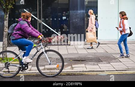 Brighton UK 2 novembre 2020 - gli acquirenti fuori a Brighton oggi passano da un uomo che dorme ruvido in un negozio chiuso porta prima del nuovo coronavirus COVID-19 restrizioni di blocco iniziare in Inghilterra il Giovedi : Credit Simon Dack / Alamy Live News Foto Stock