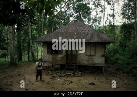 Un conservatore che posa per una foto di fronte a una casa di un contadino ai margini dell'ecosistema di Batang Toru nel villaggio di Nauli, distretto di Sitahuis, reggenza centrale di Tapanuli, provincia di Sumatra del Nord, Indonesia. Foto Stock