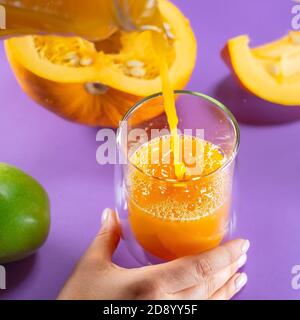 Frutta zucca mela zenzero di carota su sfondo colorato mani succo gustoso Foto Stock