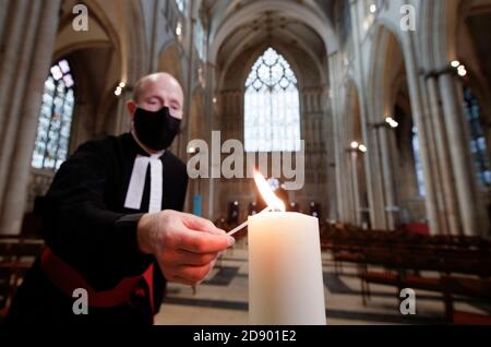 Il Revd Michael Smith, il canonico Pastore della cattedrale di York, accende una candela durante il periodo della memoria della cattedrale, che continua oggi con uno speciale "Day to Remember" coloro che sono morti durante il 2020. Foto Stock