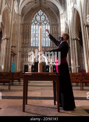 Il Revd Michael Smith, il canonico Pastore della cattedrale di York, accende una candela durante il periodo della memoria della cattedrale, che continua oggi con uno speciale "Day to Remember" coloro che sono morti durante il 2020. Foto Stock