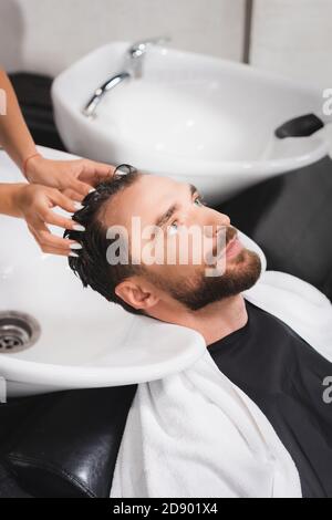 barbiere lavaggio capelli di giovane uomo bearded in salone di bellezza Foto Stock