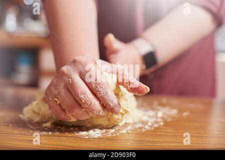 Primo piano delle mani femminili che impastano l'impasto grezzo a casa Foto Stock