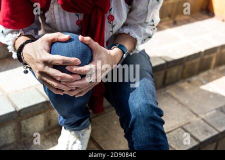 Donna seduta in dolore con ginocchia sulle scale Foto Stock