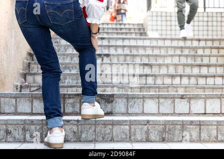 Donna con difficoltà di ginocchio che cammina su volo di scale Foto Stock
