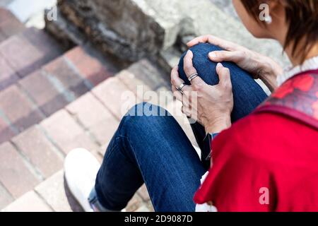 Donna seduta in dolore con ginocchia sulle scale Foto Stock