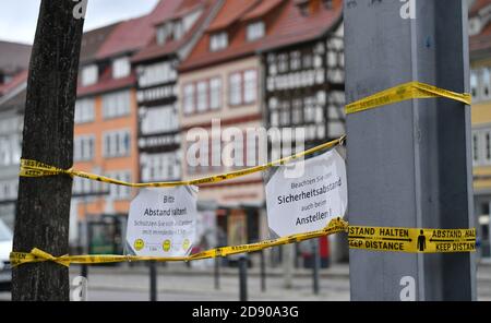 02 novembre 2020, Turingia, Erfurt: Sulla piazza della cattedrale sono attaccati dei fogli di carta con le istruzioni 'tenere la distanza' e 'mantenere la distanza di sicurezza anche quando si accodano' con nastro adesivo. A causa della pandemia di Corona, all'inizio della settimana in Turingia sono in vigore numerose restrizioni significative nella vita pubblica. Come in altri stati federali, tutta la gastronomia, ad eccezione di confettorie e mense, così come la maggior parte delle strutture culturali e di svago dovranno chiudere. Le restrizioni di contatto si applicano al pubblico. Foto: Martin Schutt/dpa-Zentralbild/dpa Foto Stock