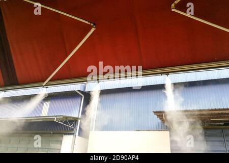 Il sistema di raffreddamento a nebbia d'acqua abbassa la temperatura ambiente del ristorante Foto Stock