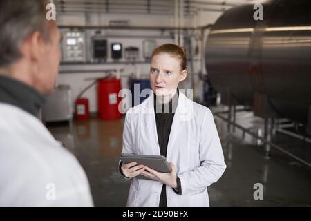 Vita in su ritratto di giovane donna che parla con il supervisore o il responsabile mentre discute il lavoro alla fabbrica di produzione di cibo, copy space Foto Stock