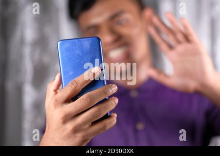Sorridente giovane che usa il suo telefono per fare un video chiama Foto Stock