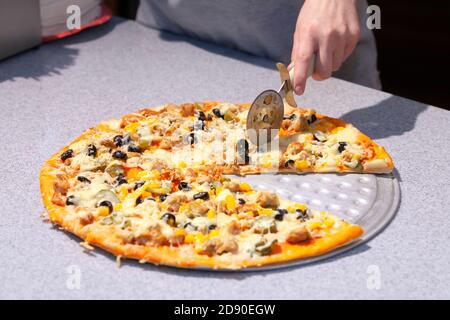Chef che taglia la pizza appena sfornata Foto Stock