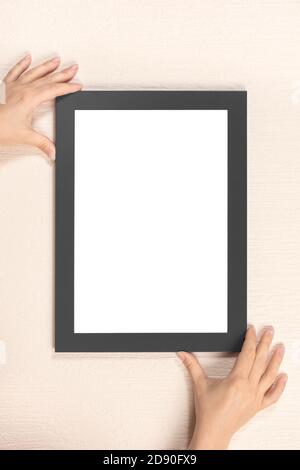 cornice lurning, le mani appendono al muro nero telaio mockup Foto Stock