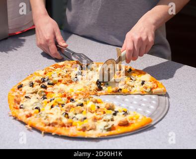Chef che taglia la pizza appena sfornata Foto Stock