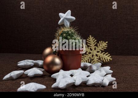 Albero di Natale creativo, cactus con palla d'oro e decorazione fiocco di neve e stelle lucenti, concetto di fondo carta regalo su sfondo marrone Foto Stock