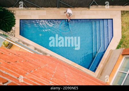 vista dall'alto dell'uomo che pulisce una piscina Foto Stock