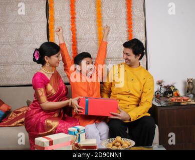 Coppia che dà doni al loro figlio sul festival di Diwali. Foto Stock