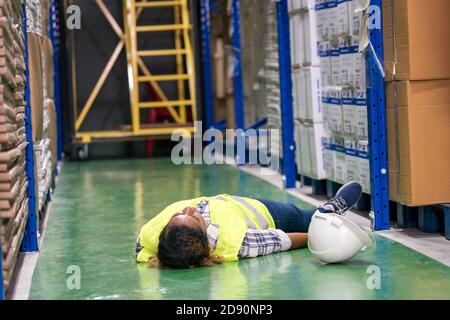 African black warehouse manager lying down. On factory ground after injured from accident while working. Using for industrial safety first and busines Foto Stock