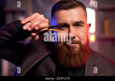 ritratto di barbiere professionista che tiene in mano le forbici, è pronto a tagliare i capelli o la barba Foto Stock