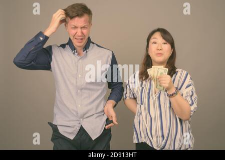 Giovane bell'uomo d'affari e matura donna d'affari asiatica su sfondo grigio Foto Stock