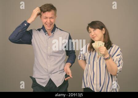 Giovane bell'uomo d'affari e matura donna d'affari asiatica su sfondo grigio Foto Stock