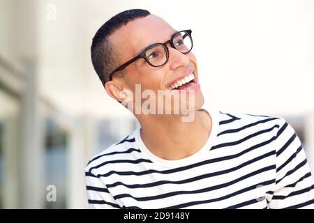 Primo piano ritratto di giovane uomo con occhiali ridendo e. guardando in alto Foto Stock